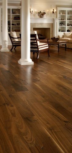 a living room with wood floors and white columns in the center, along with an open fireplace