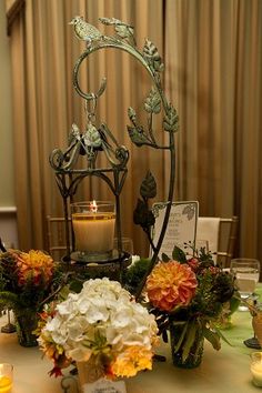 an arrangement of flowers and candles on a table