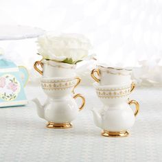 two white tea cups with gold trimmings and a flower