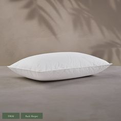 a white pillow sitting on top of a cement floor next to a wall with shadow