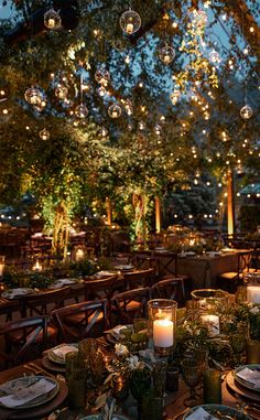 the tables are set with candles, plates and place settings for an outdoor dinner party