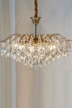 a chandelier hanging from the ceiling in a room with white walls and curtains