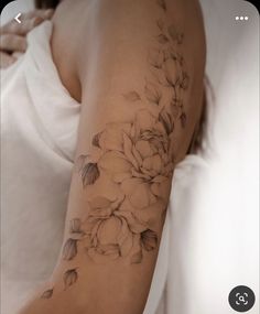 a woman's arm with flowers and leaves tattooed on the arm, in black and white