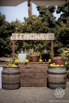 an outdoor lemonade stand with two wooden barrels filled with lemons