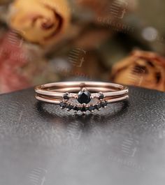 a black diamond ring sitting on top of a table next to some roses and flowers