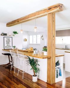 an open concept kitchen and dining area with wood flooring, white walls and wooden beams