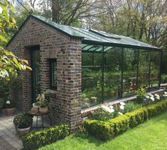 a small brick building sitting in the middle of a garden