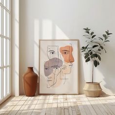 an art work is displayed on the wall next to a vase and potted plant