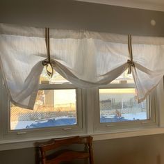 two windows with white curtains hanging from them