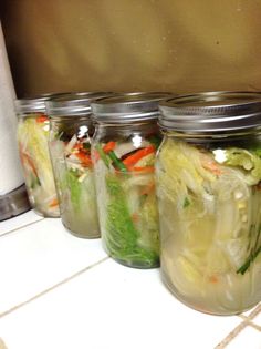 four mason jars filled with different types of vegetables