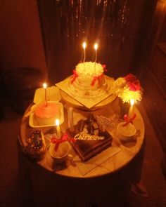 a birthday cake sitting on top of a table with lit candles in the middle and other decorations around it