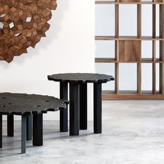 three black tables sitting next to each other in front of a wall with wood pieces on it