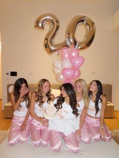 a group of women in matching pink and white outfits posing for a photo with balloons