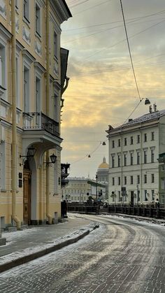 an empty street with snow on the ground and buildings in the backgrouds