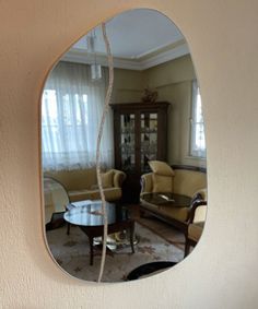 a mirror hanging on the side of a wall next to a couch and coffee table