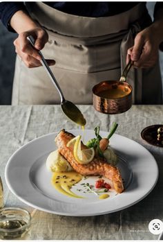 a chef is preparing food on a plate with spoons and utensils in his hands