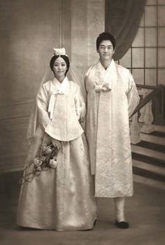 an old photo of two people dressed in traditional japanese wedding attire, standing next to each other