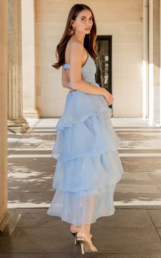 a woman in a blue dress is standing outside