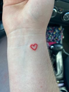 a small red heart tattoo on the wrist