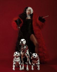 a woman in black and white with dalmatian dogs on red background, posing for the camera