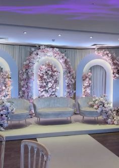 a room decorated with flowers and couches in front of a white stage set up