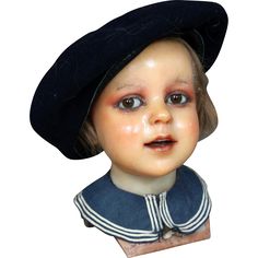 an antique doll head wearing a black hat