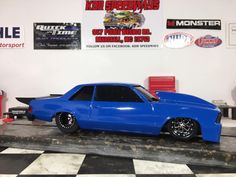 a blue toy car sitting on top of a black and white checkered floor