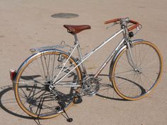 a silver bicycle parked on top of a sandy beach next to a manhole hole