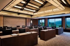 an empty conference room with tables and chairs in front of large windows looking out onto the mountains