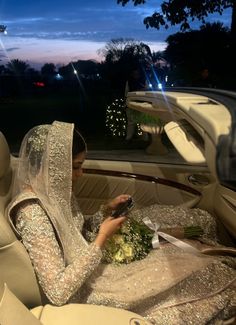 a woman sitting in the back seat of a car looking at her cell phone while holding broccoli