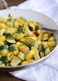 a white bowl filled with zucchini and other vegetables