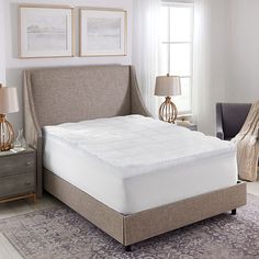 a bed with a white mattress in a bedroom next to a chair and lamp on a rug