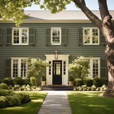 a large gray house with white windows and shutters on the front door is shown