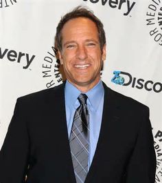 a man in a suit and tie smiling for the camera