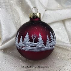 a red ornament with white trees on it sitting on a white cloth covered table