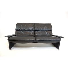 a black leather loveseat sitting on top of a white floor