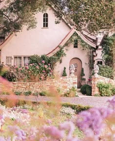 a white house surrounded by flowers and trees