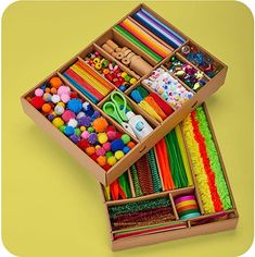 an open cardboard box filled with lots of different colored crafting supplies on a yellow background