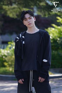 a young man is standing on the street wearing black sweatpants and a hoodie