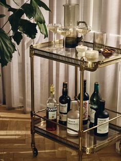 a gold bar cart with bottles and glasses on it