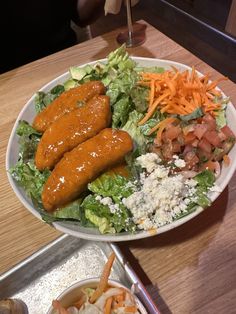 a salad with carrots, lettuce and other vegetables on the plate next to it