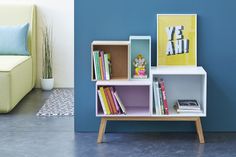 a white shelf with books and pictures on it next to a blue wall in a living room