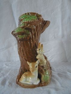 two deer figurines sitting on top of a tree stump