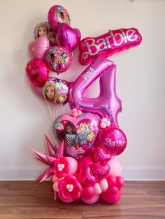 pink balloon bouquet with barbie number four and balloons in the shape of hearts on wooden floor