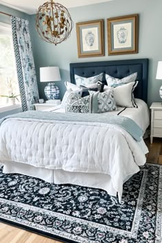 a bedroom with blue and white bedding, chandelier, rugs and pictures on the wall