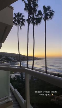 the view from an apartment balcony at sunset with palm trees and ocean in the background