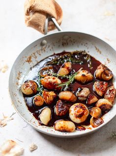 a white bowl filled with cooked scallops and sauce on top of a table