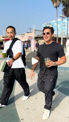 two men walking down the street with drinks in their hands