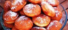 a glass bowl filled with powdered sugar covered donuts