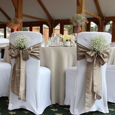 two white chairs with bows and baby's breath flowers on them are set up for a wedding reception